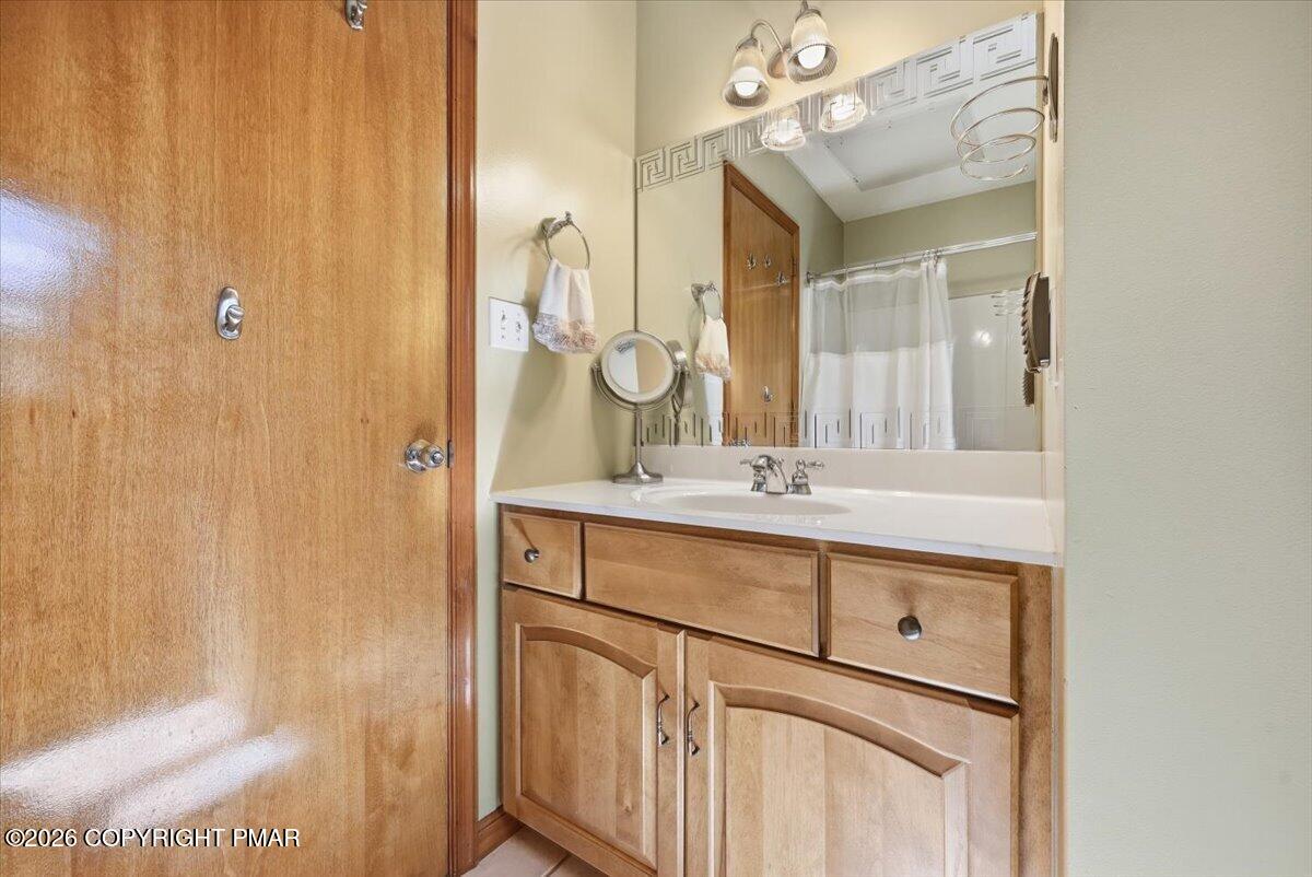 Bathroom vanity with wood cabinetry, a white sink and countertop, and a large mirror.