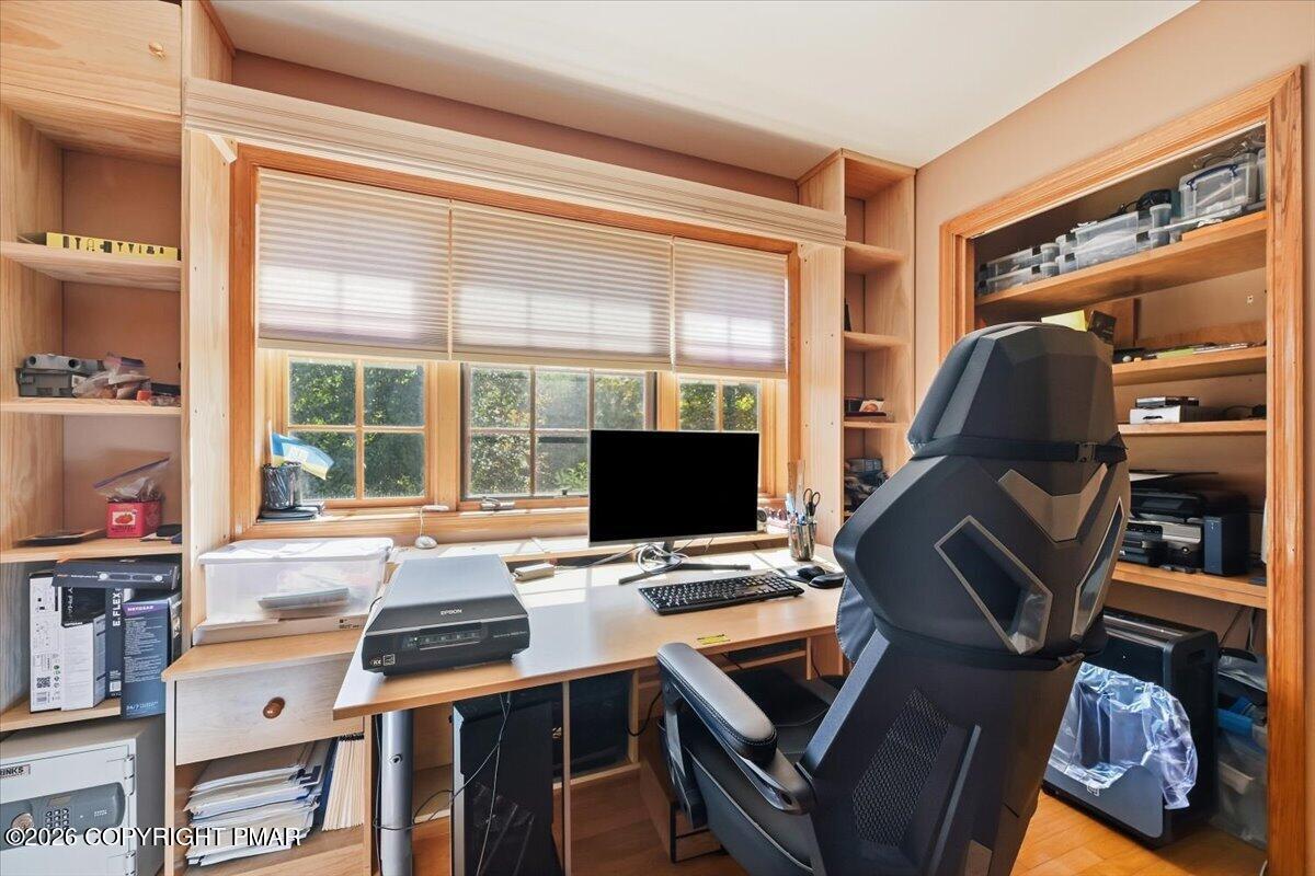 Home office with a wooden desk, built-in shelves, and a large window.