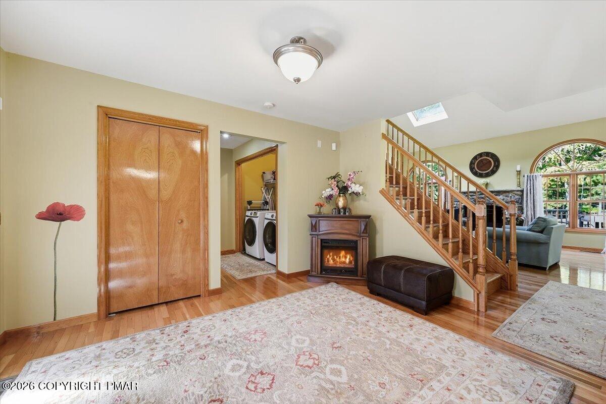 Furnished living room with a wooden staircase, fireplace, and laundry area.