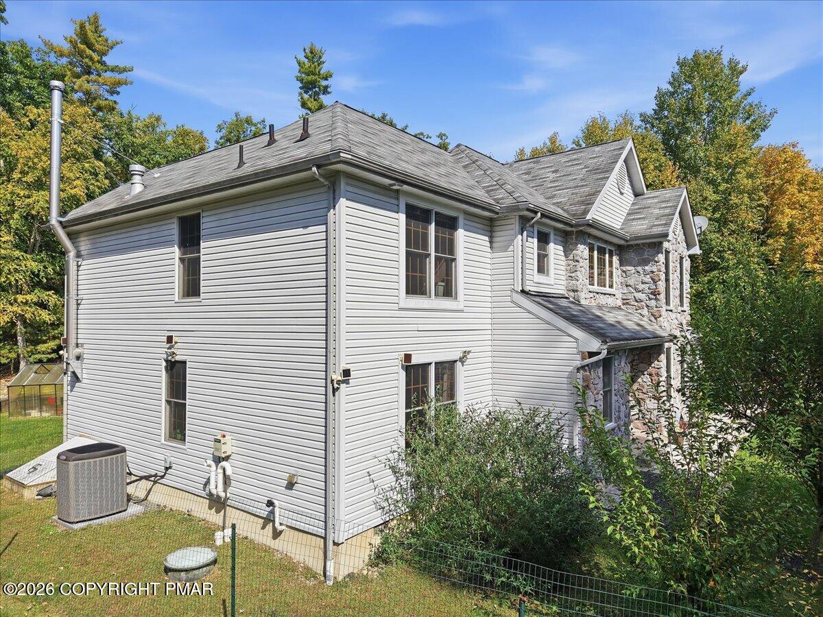 Two-story home with gray siding, a stone facade, and trees around the yard.