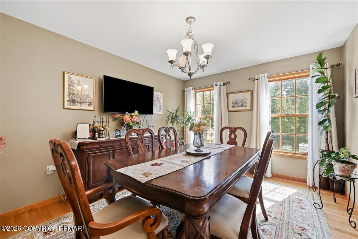 Dining room with a dark wood table, carved chairs, and tall curtained windows.