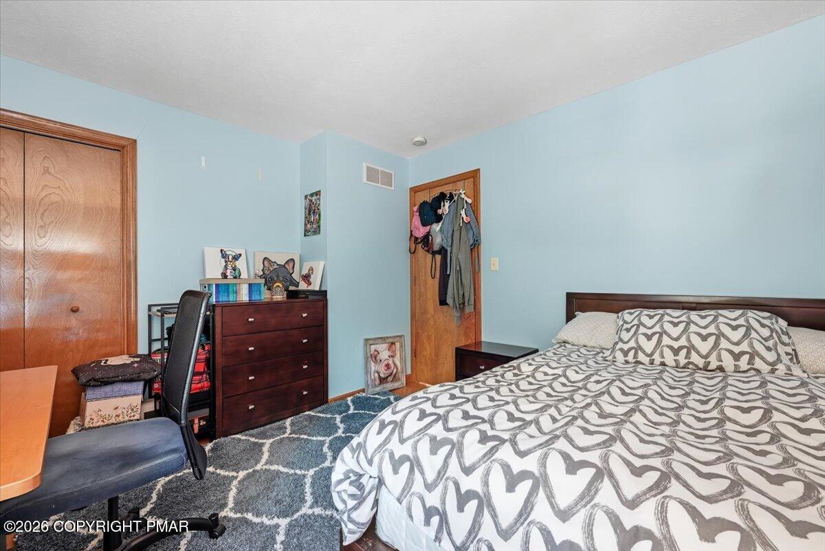 Bedroom with light blue walls, heart-patterned bedding, and dark wood furniture.