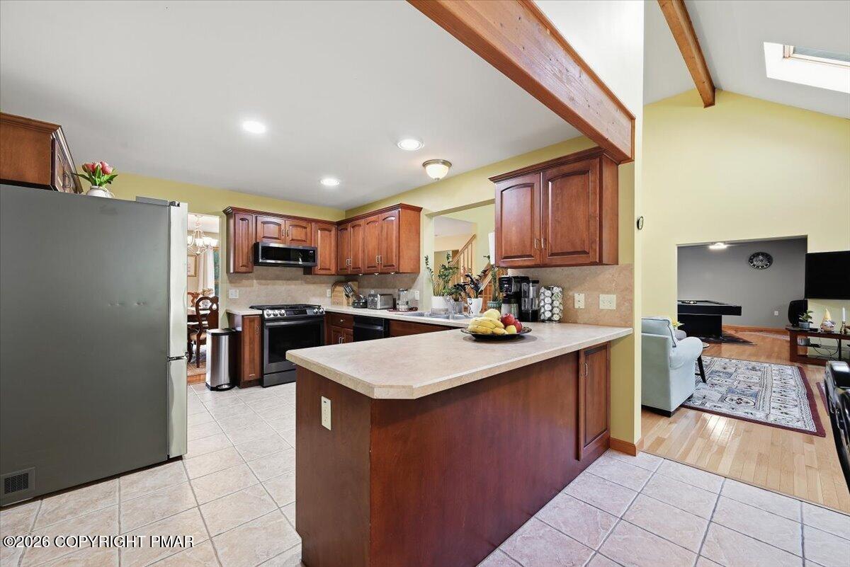 Kitchen with a large island, dark wood cabinets, and exposed beams opening to the living room.