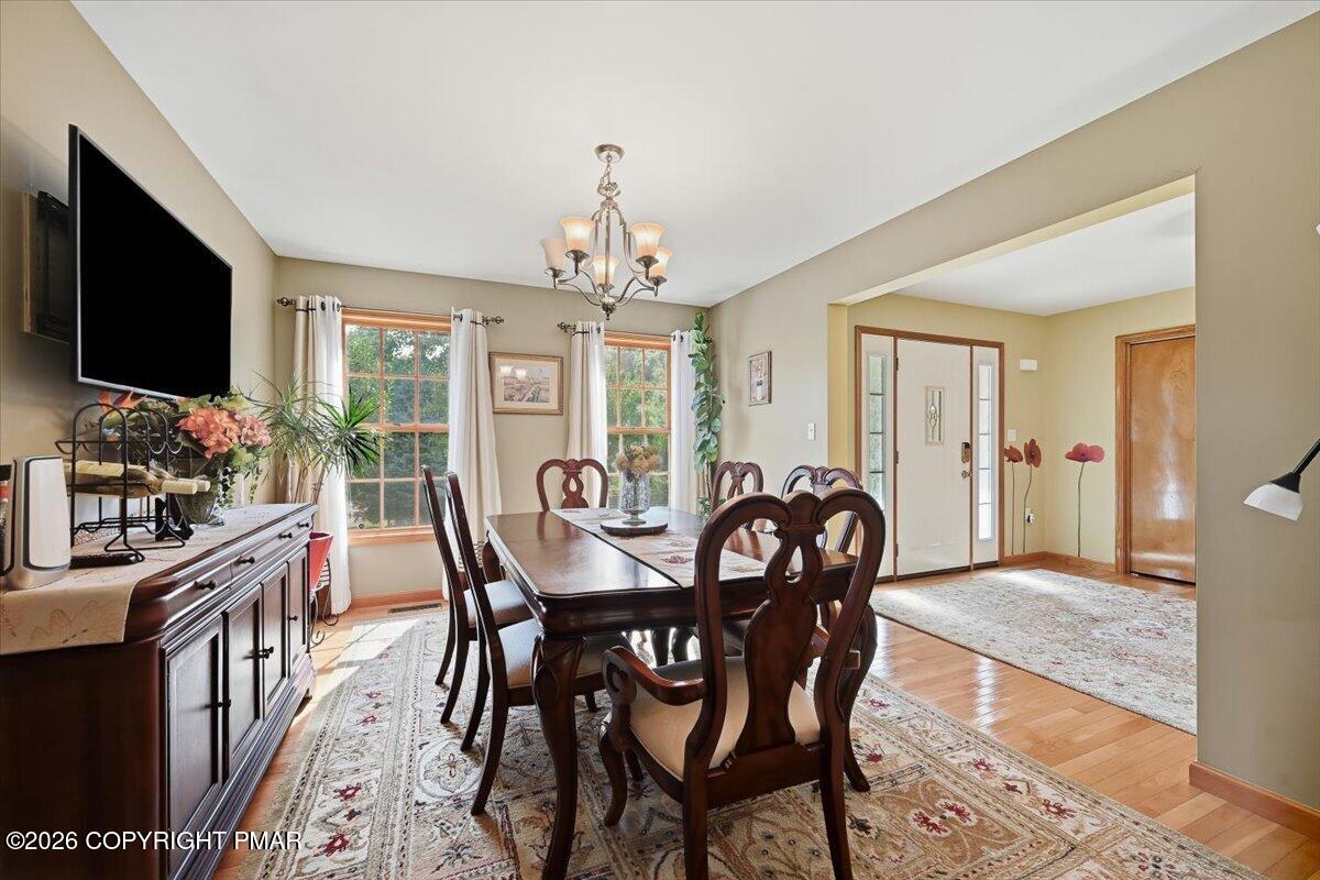 Dining room with a dark wood table, carved chairs, chandelier, and large windows.
