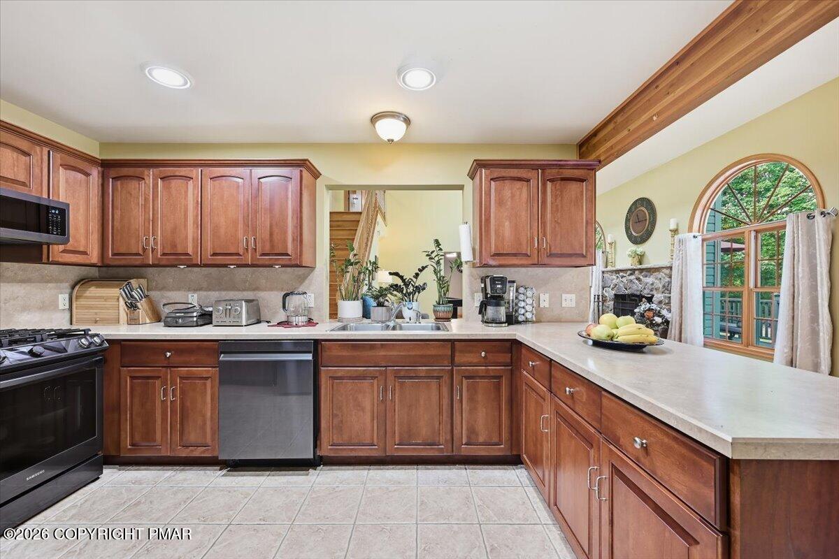 Kitchen with reddish-brown wood cabinets, a long peninsula, and a large arched window.