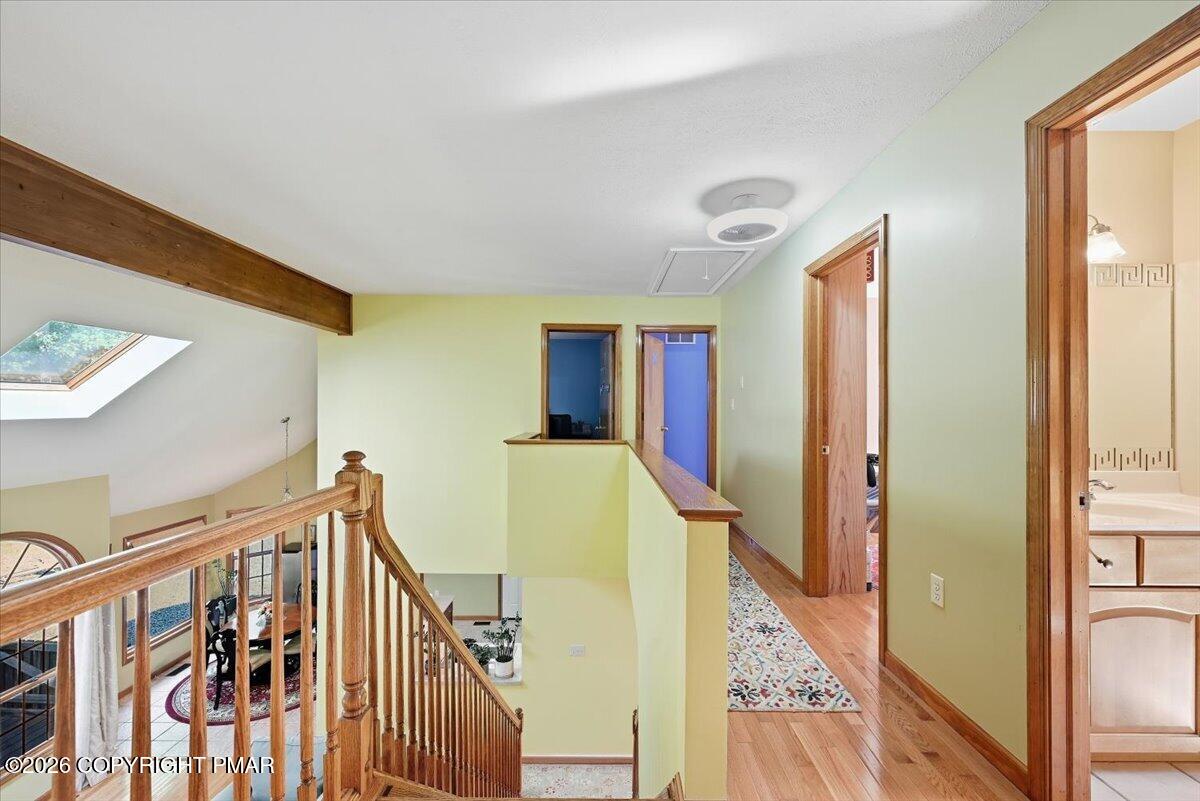 Upstairs hallway overlooking the staircase, with a skylight and wood railing.