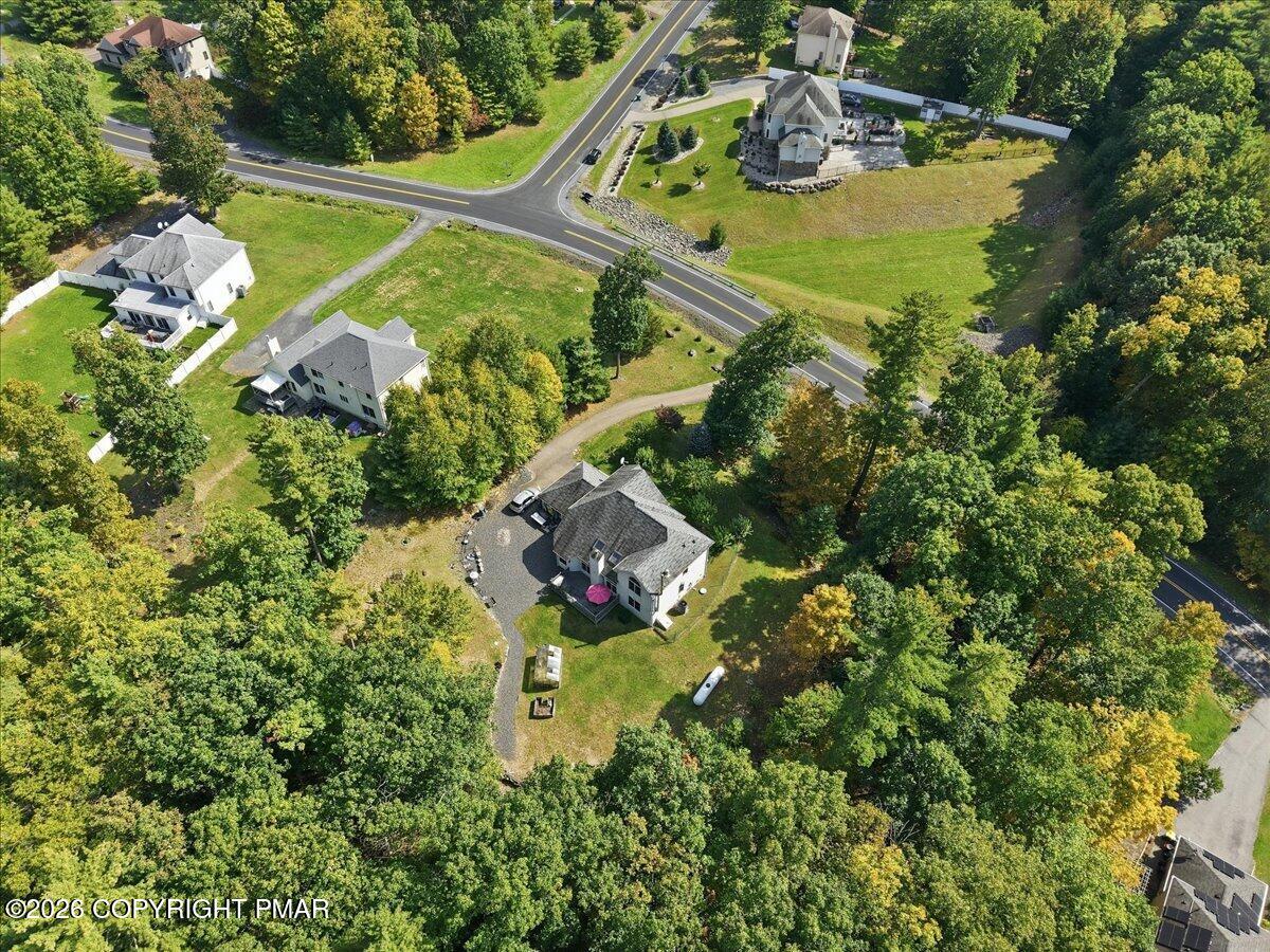 Aerial view of detached homes among wooded lots beside a winding road.