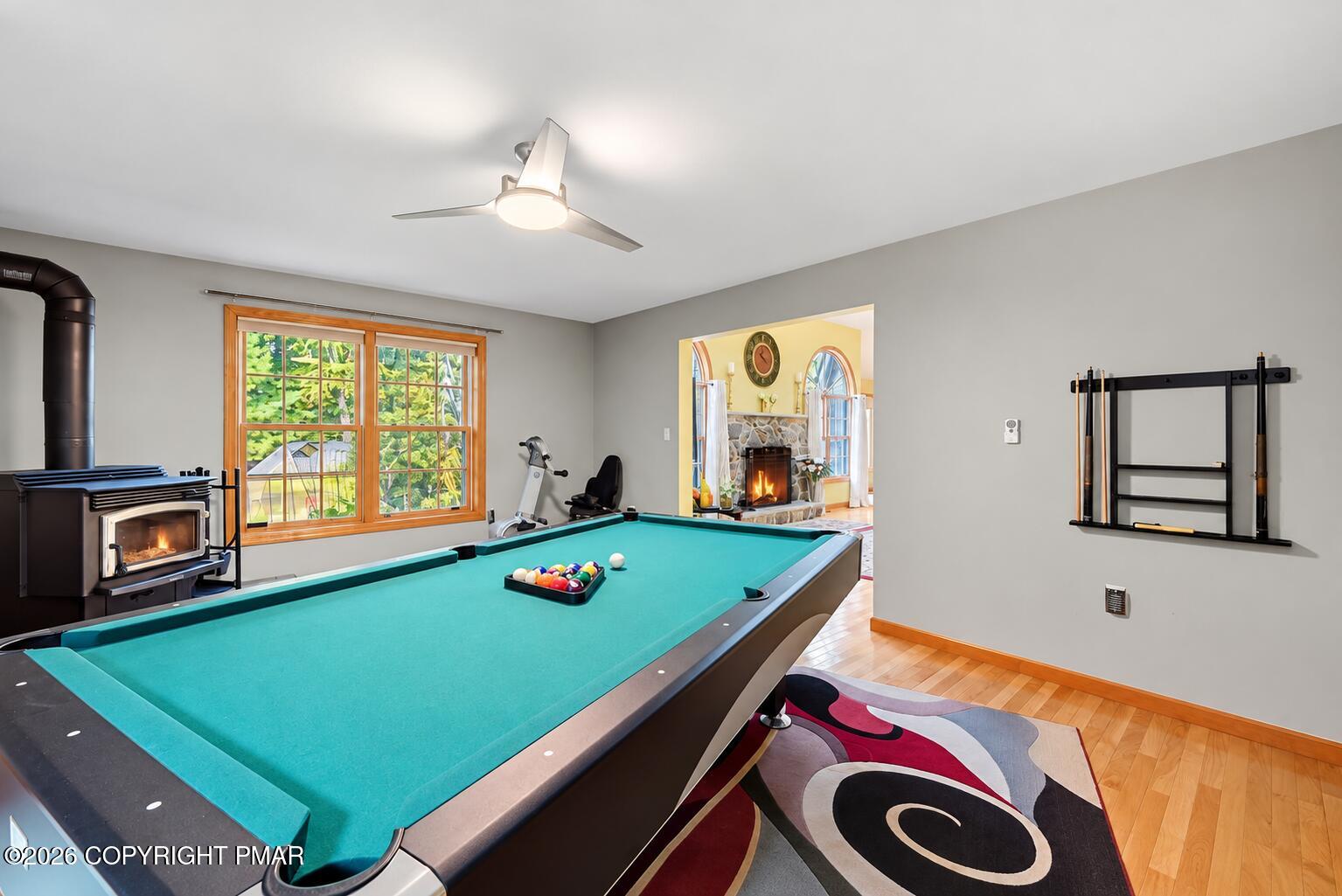Game room with a turquoise pool table, wood-burning stove, and doorway to a stone fireplace.