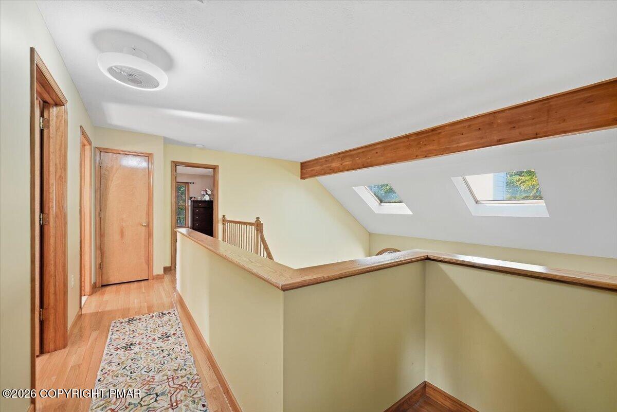 Upper-floor hallway with hardwood floors, wood trim, and two skylights overlooking the stairwell.