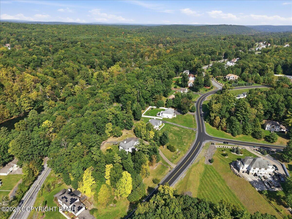 Aerial view of homes along a curving road amid dense woodland.