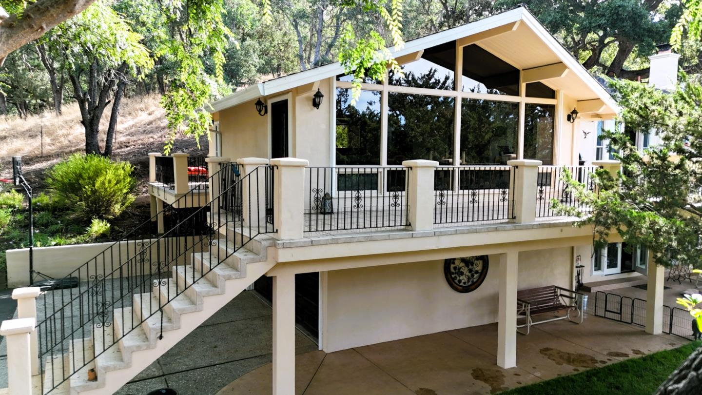 Cream-colored home with a large elevated terrace, black railings, and a wide outdoor staircase.