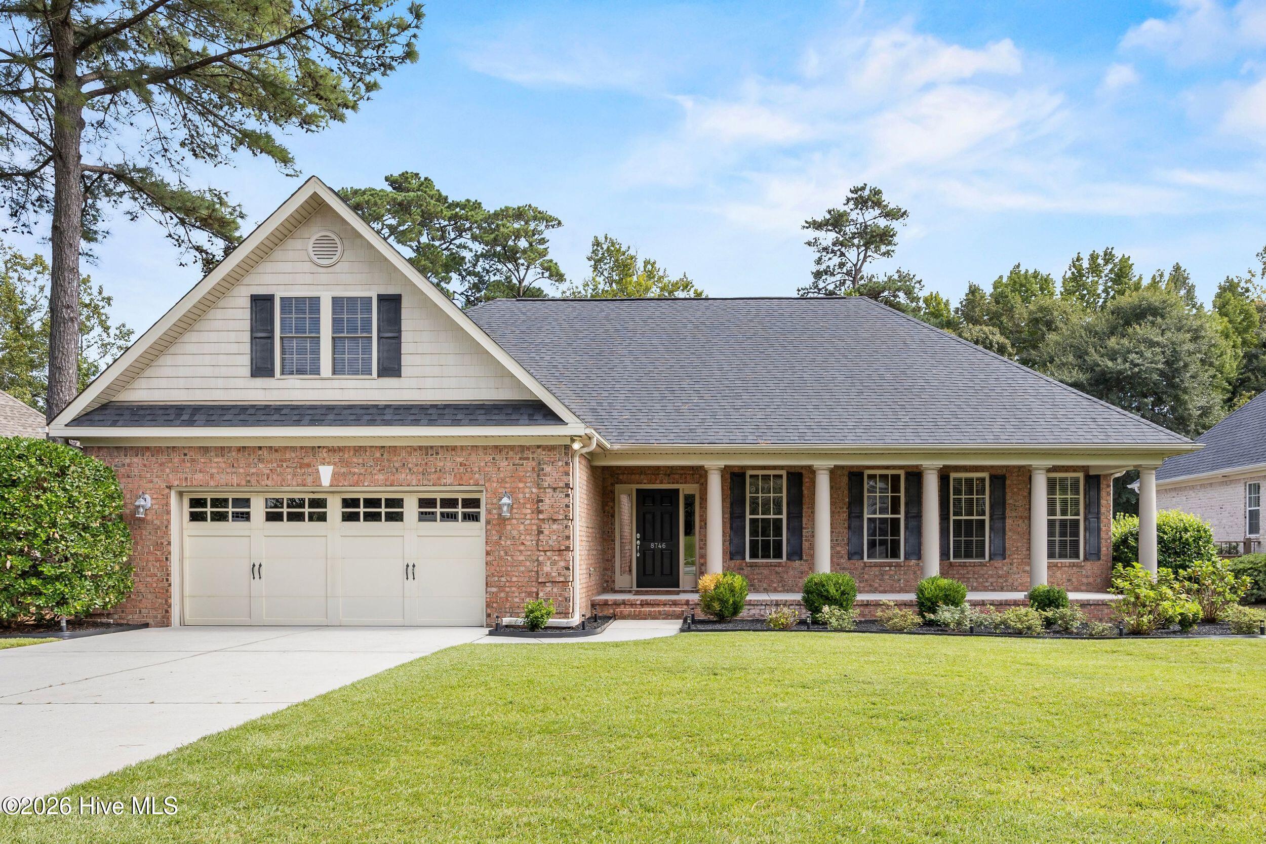 Brick home with a front-facing gable, two-car garage, and columned covered porch.