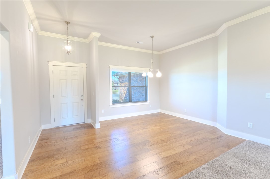 Empty dining room with wood flooring, a large window, and two ceiling light fixtures.
