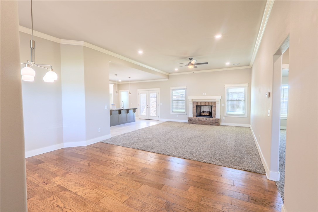 Open-plan living room with hardwood floors, carpeted area, and stone fireplace.