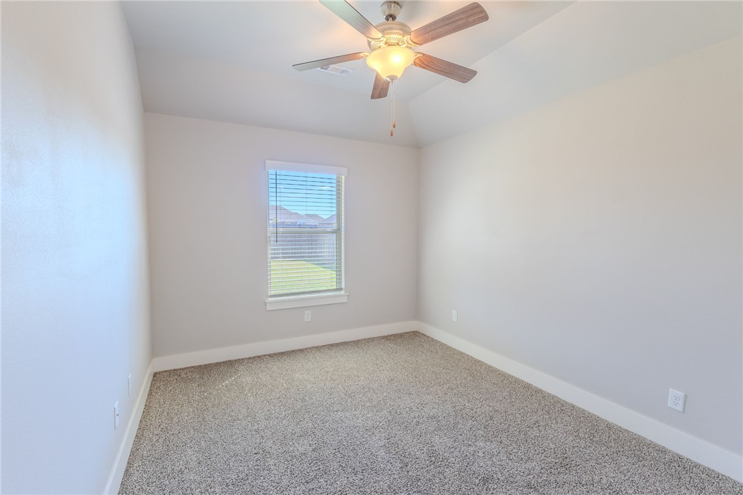 Vacant carpeted room with a window and ceiling fan with a lit fixture.