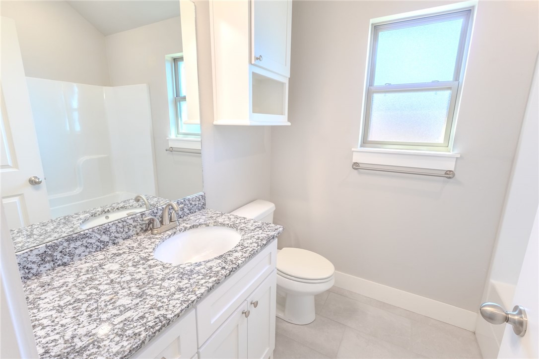 Bathroom with a granite vanity, white cabinetry, and a tub-shower combination.
