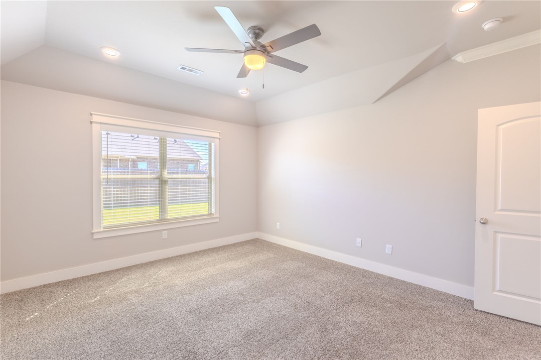 Empty bedroom with beige carpet, window blinds, ceiling fan, and high ceiling.
