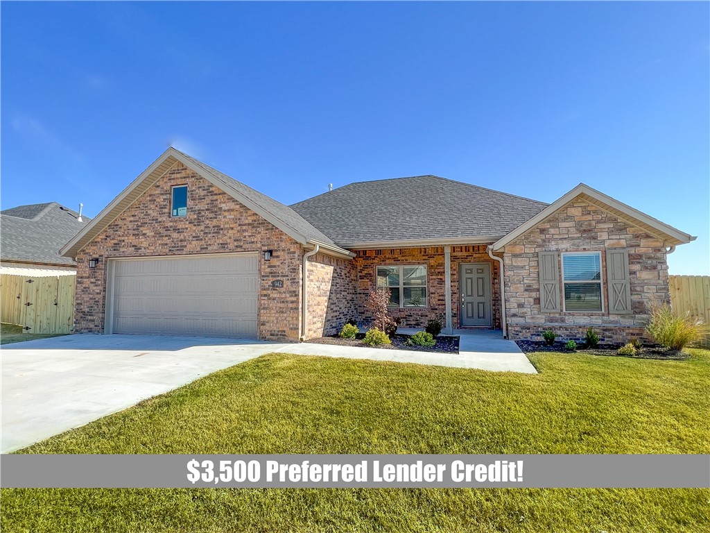 Brick and stone house with an attached garage, broad driveway, and front lawn.