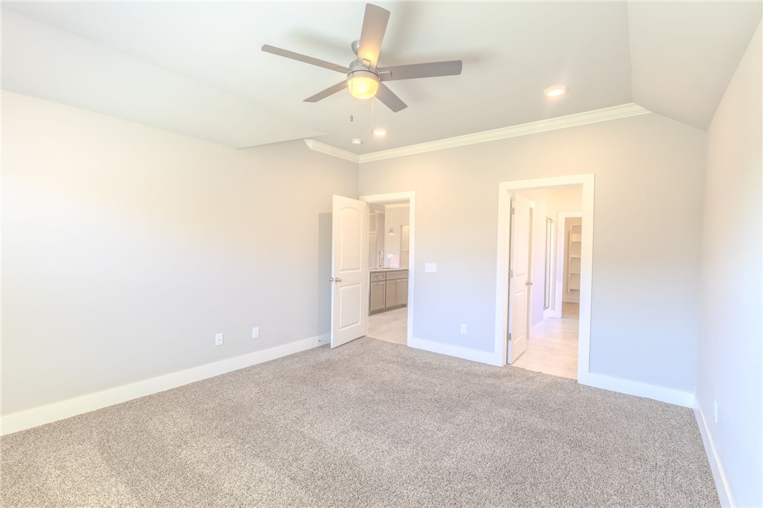 Empty carpeted bedroom with a ceiling fan and two open doorways.