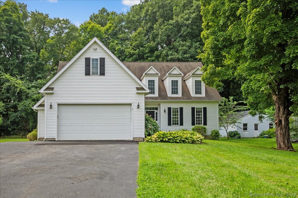 White two-story house with black shutters, three dormers, and a large attached garage.