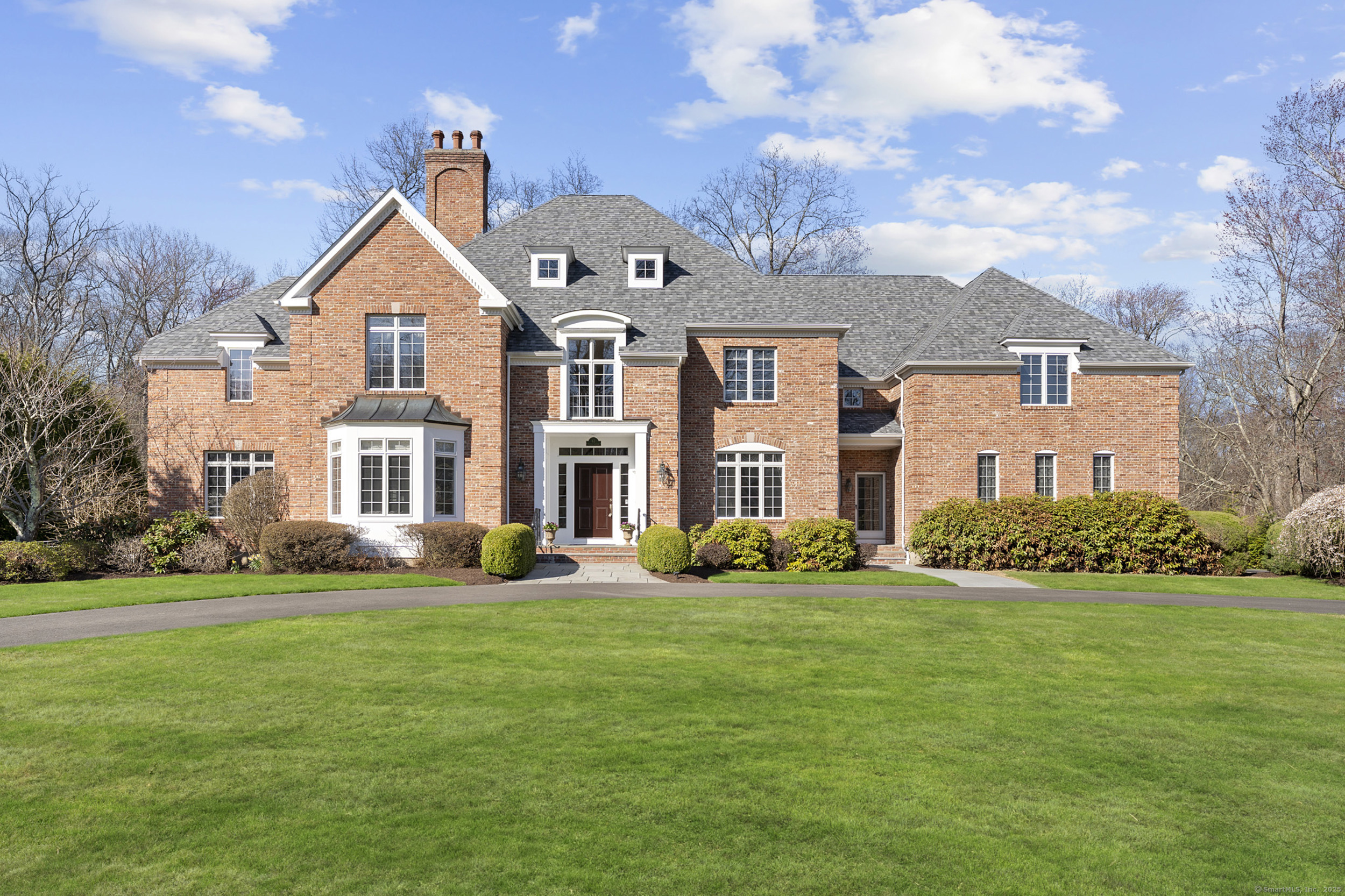 Large red-brick house with a gray roof, white-trimmed windows, and broad green lawn.