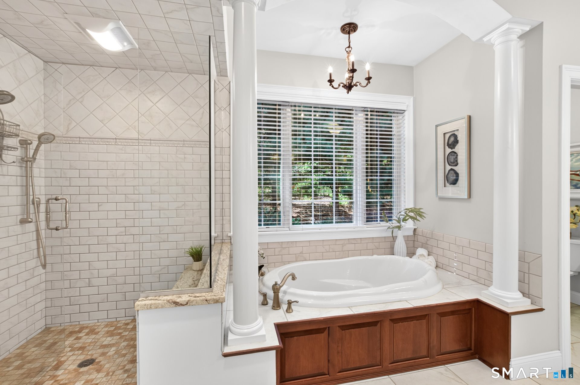 Bathroom with a tiled glass shower and corner soaking tub beneath a wide window.