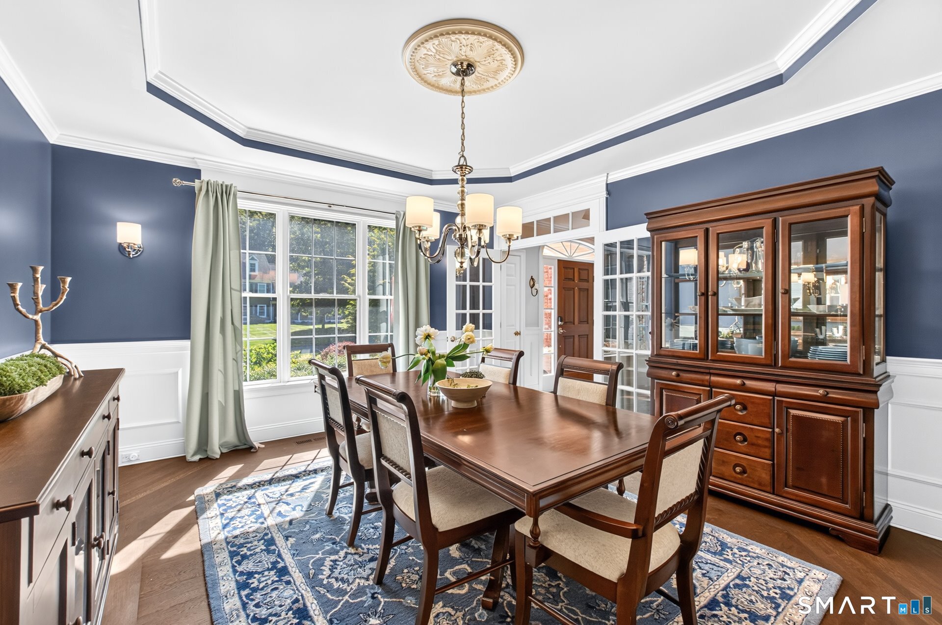 Dining room with a dark wood table, blue patterned rug, and glass-front china cabinet.
