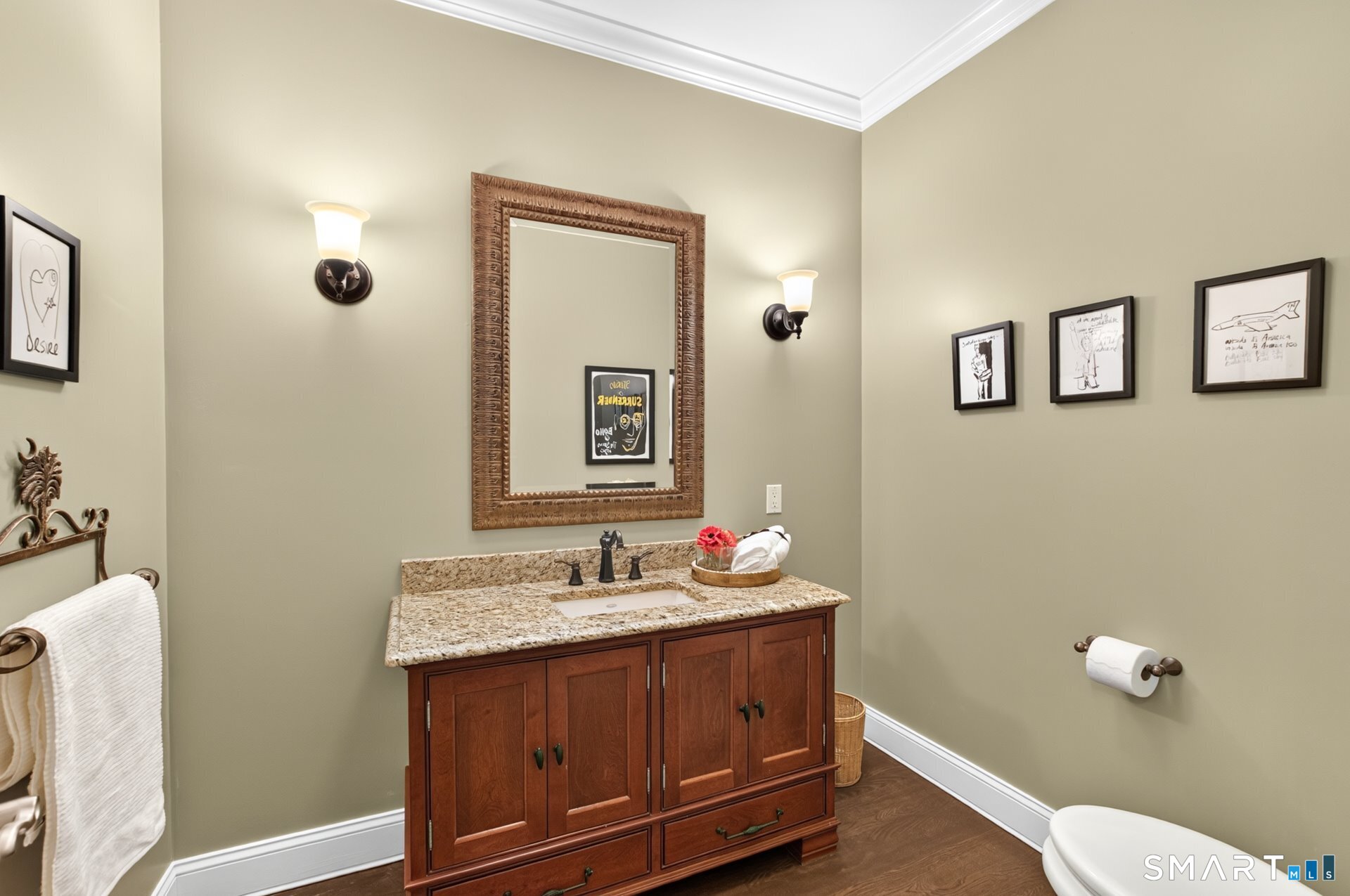 Bathroom vanity with a granite countertop, ornate framed mirror, and paired wall sconces.