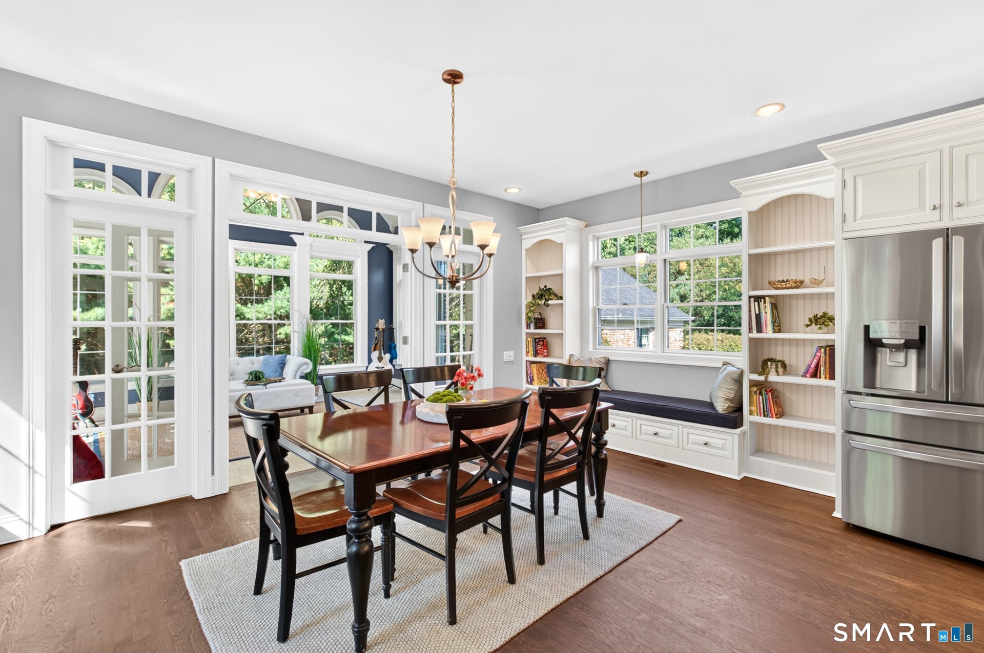 Dining area with built-in white bookshelves, a window seat, and a dark wood table.