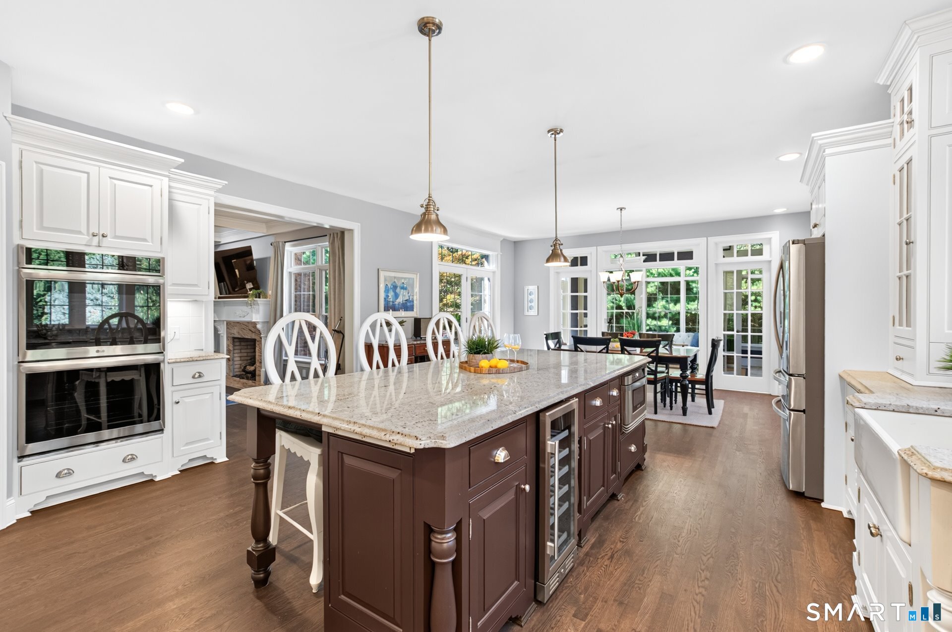 Kitchen with a large dark wood island, stone countertop, white cabinetry, and adjoining dining area.