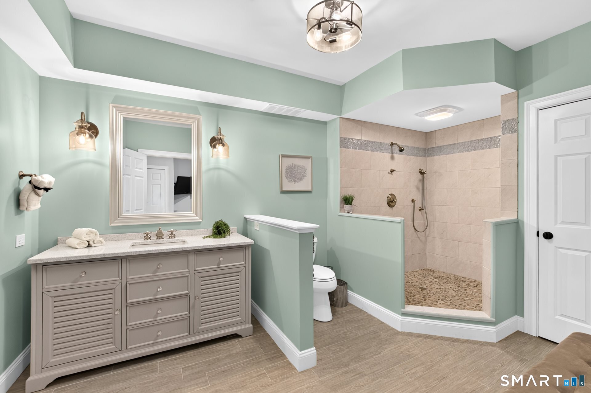 Bathroom with sage-green walls, a gray vanity, and a spacious tiled walk-in shower.