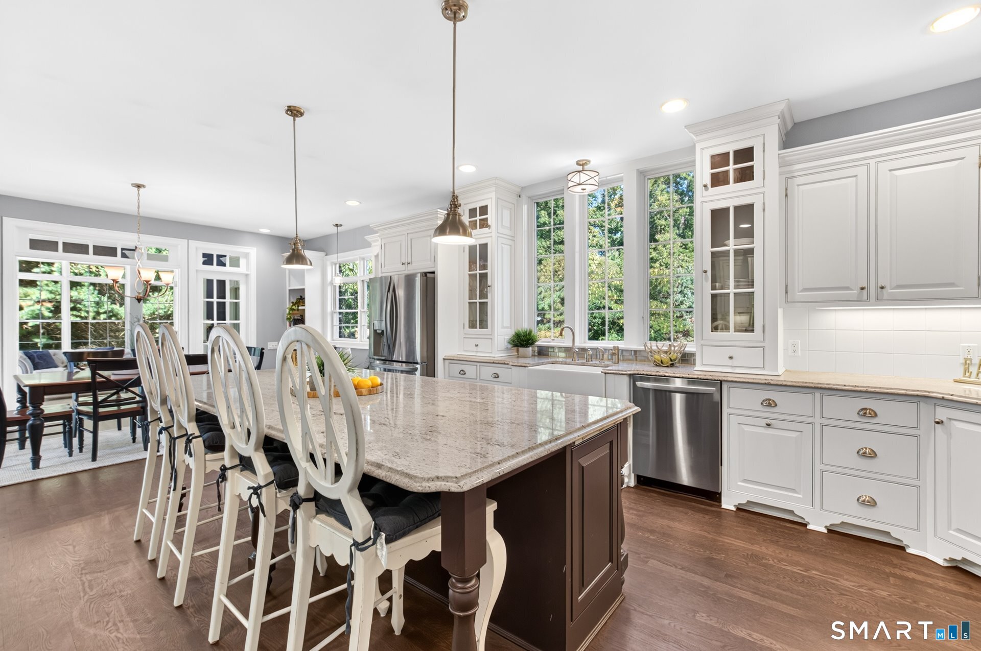 Bright kitchen with a large granite island, white cabinetry, and an adjoining dining area.