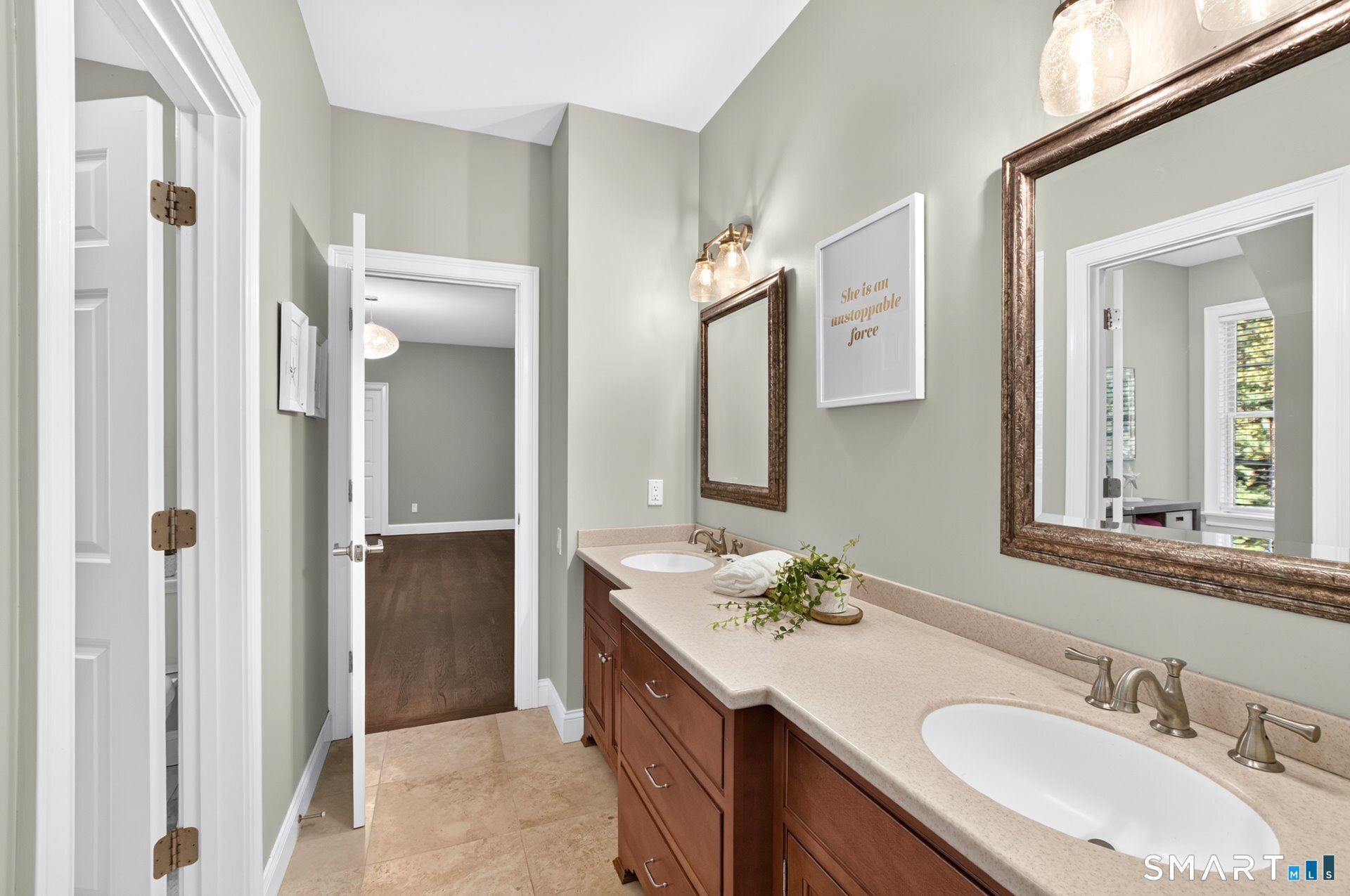 Bathroom with a long double vanity, warm wood cabinets, stone countertop, and framed mirrors.
