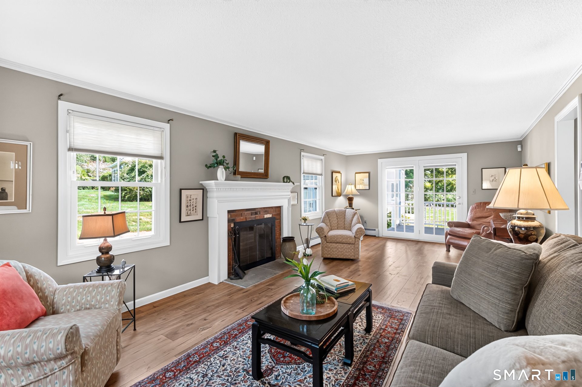 Furnished living room with a brick fireplace, hardwood floors, and French doors to a deck.