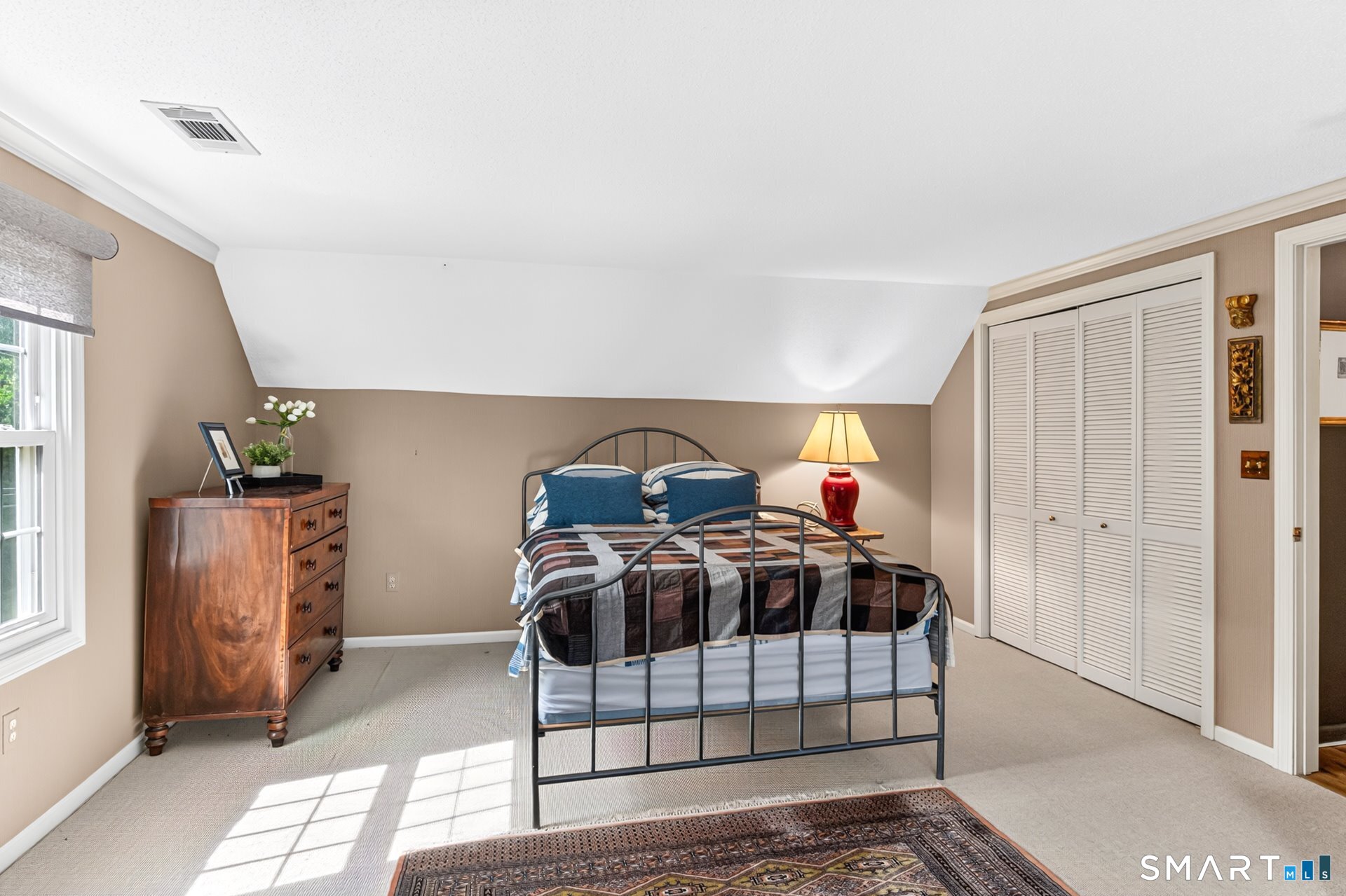Bedroom with a black metal bed, blue pillows, and a sloped ceiling.
