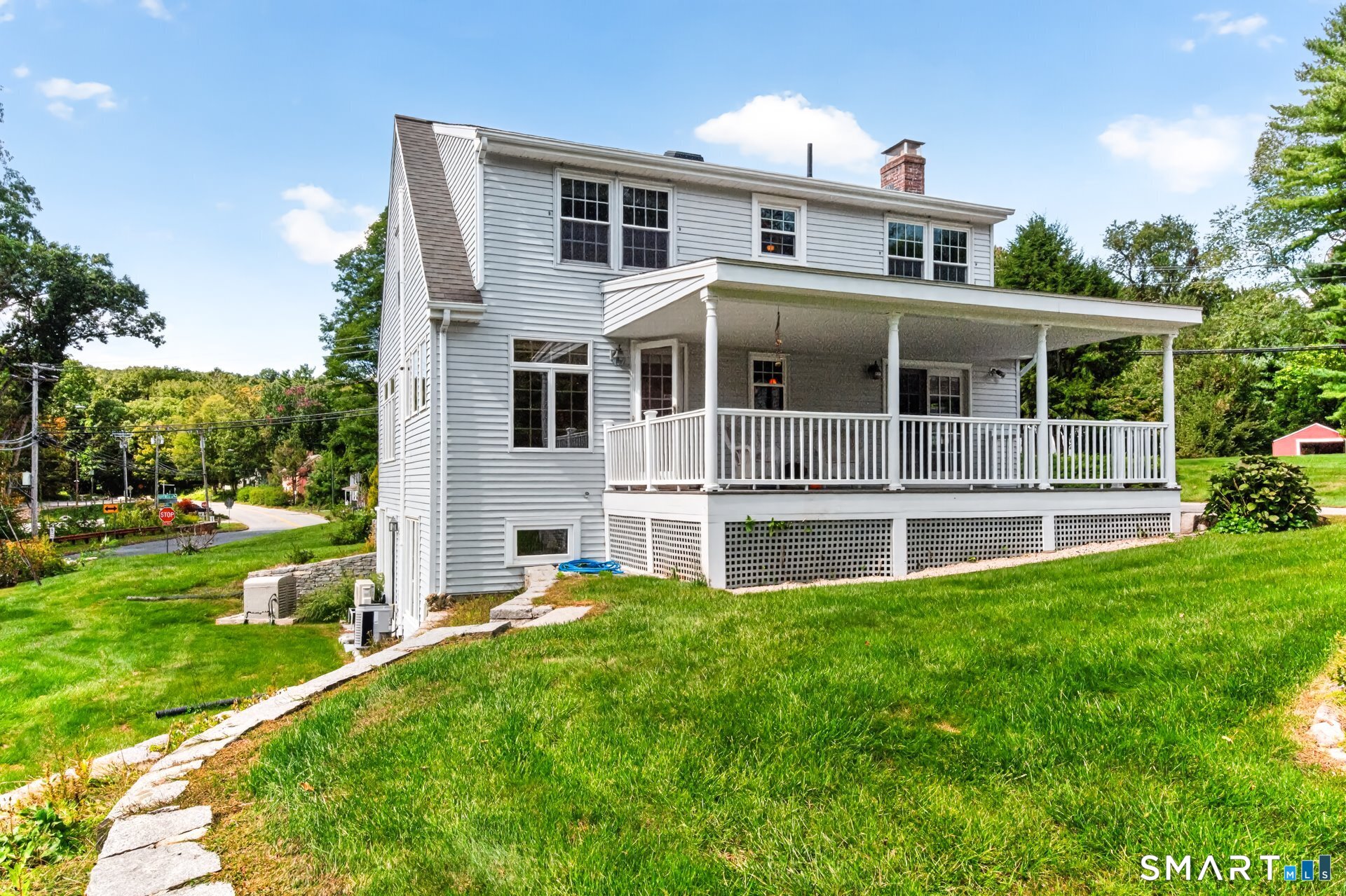 White two-story house with a broad covered porch and sloping lawn.