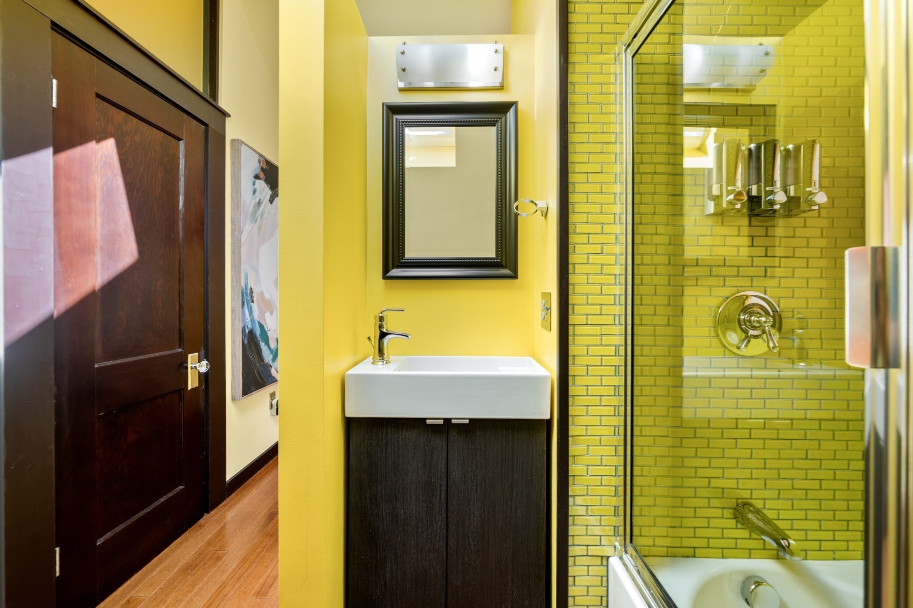 Bathroom with a dark wood vanity and a glass-enclosed, yellow-green tiled shower.