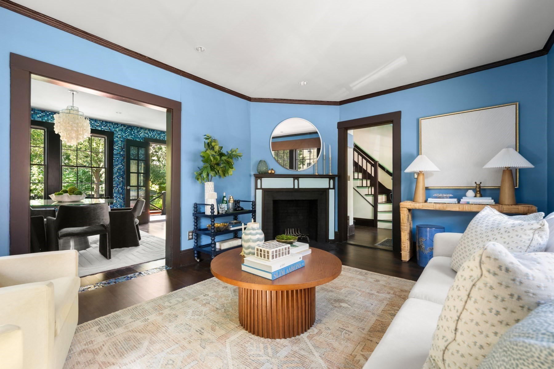 Living room with blue walls, a central fireplace, and an adjoining dining area with mosaic tile.