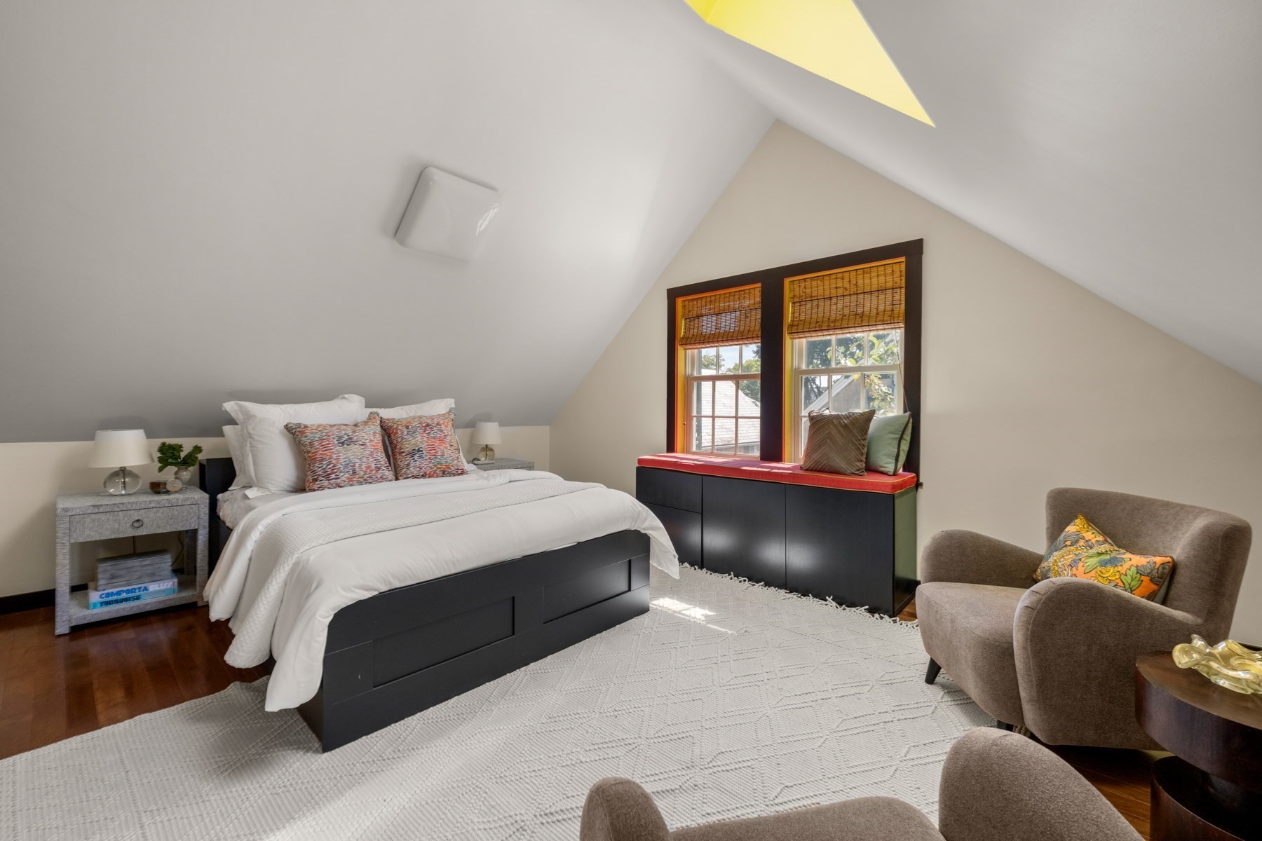Attic bedroom with a white bed, sloped ceiling, and cushioned window seat.