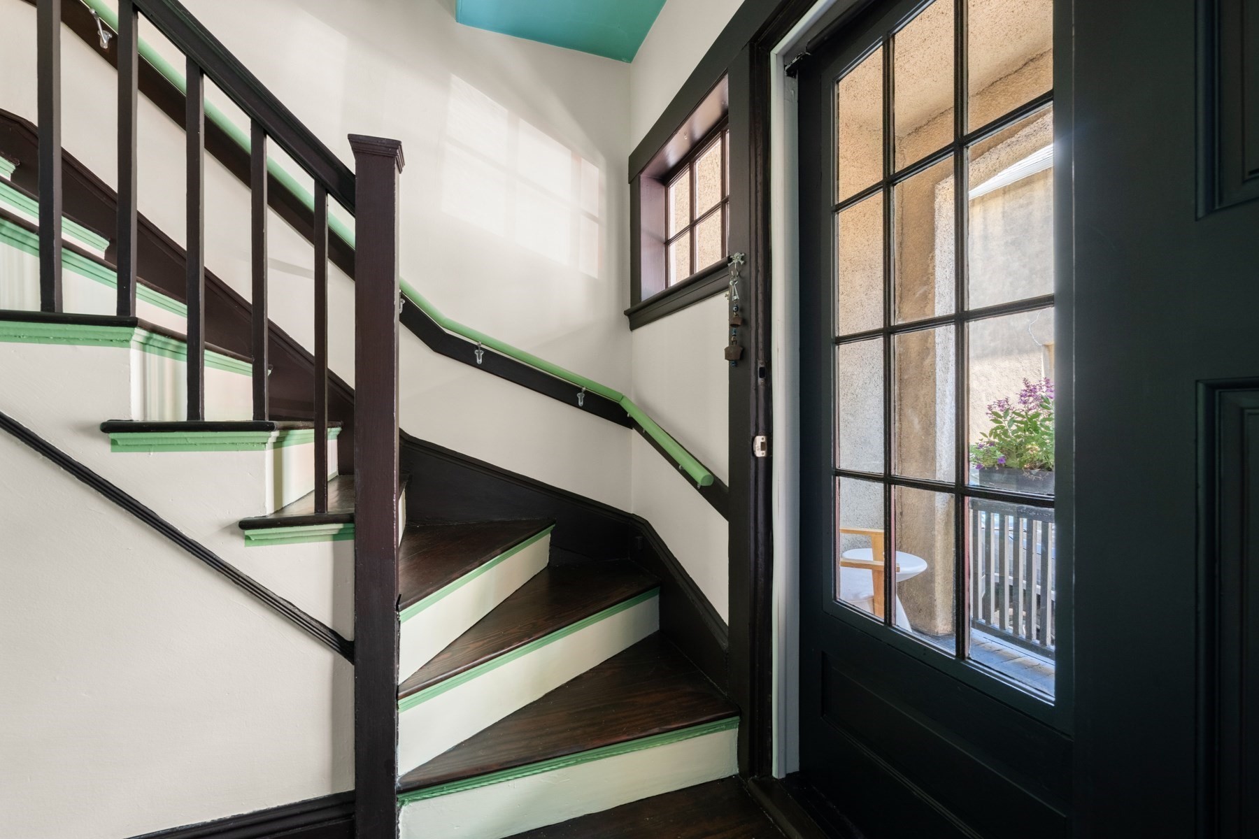 Entryway staircase with dark wood steps, green trim, and a glass-paneled door.