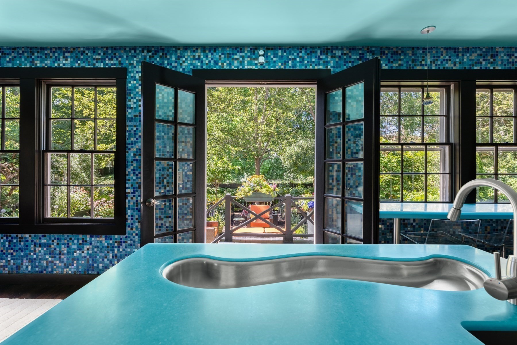 Indoor spa pool with blue mosaic tile and open doors to a garden patio