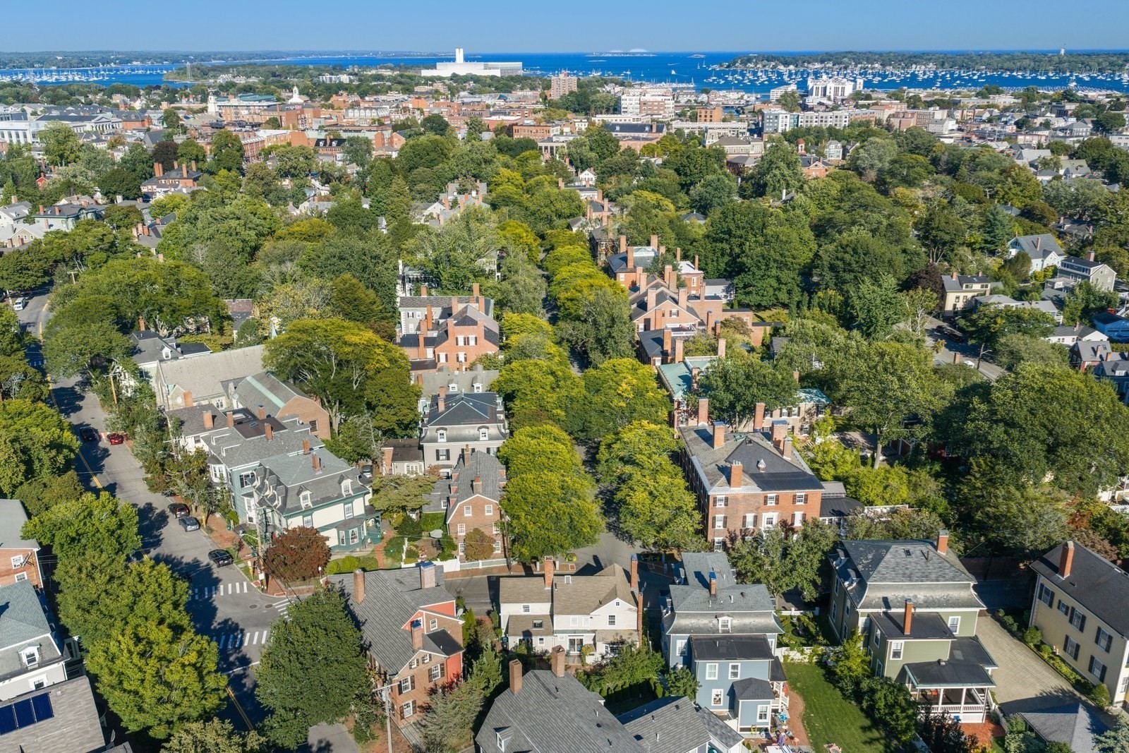 Aerial view of a leafy residential neighborhood with Salem Harbor and boats in the distance.