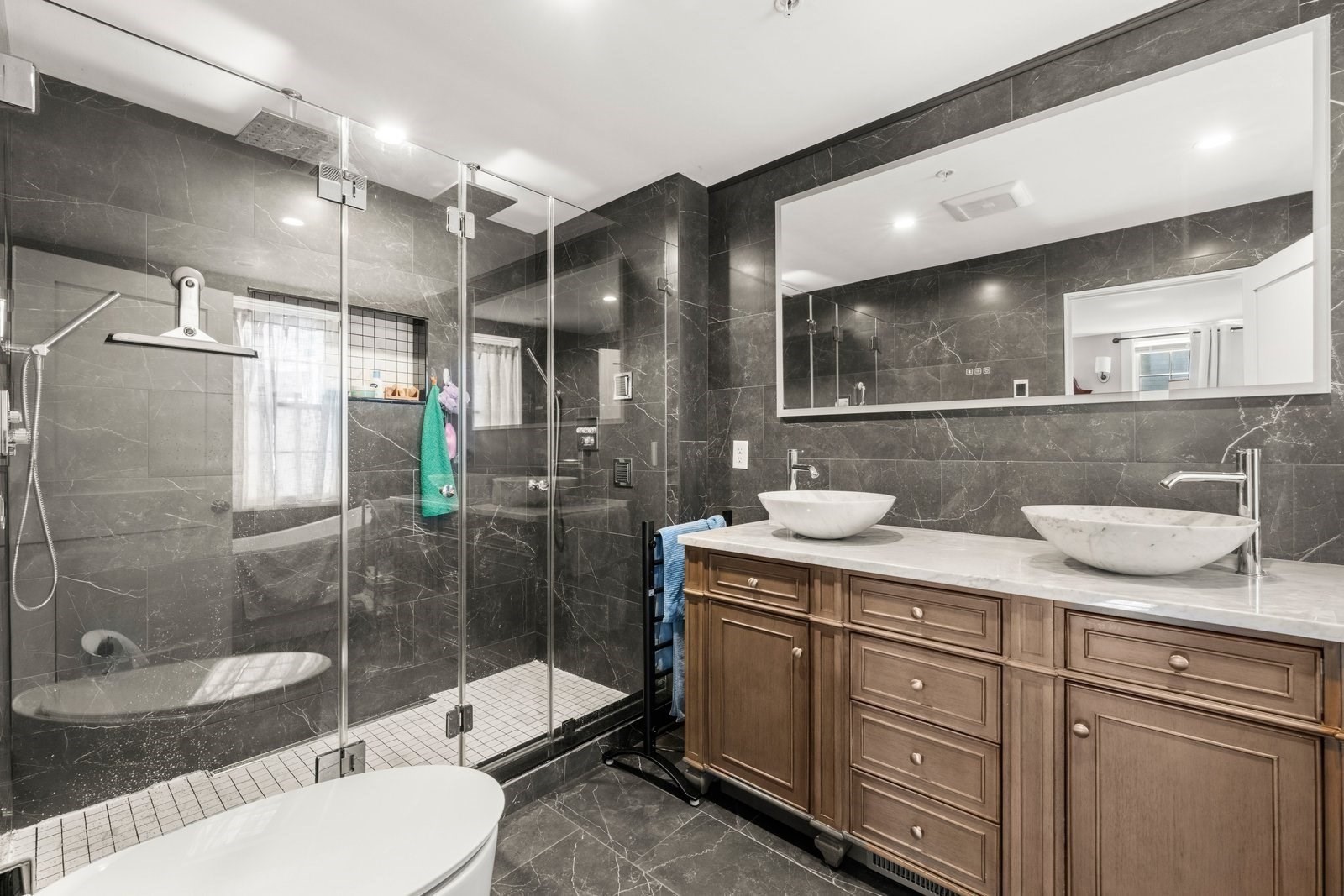 Bathroom with a glass shower, freestanding tub, and wood double vanity with two vessel sinks.