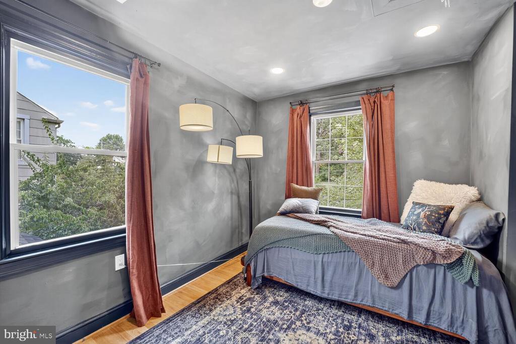 Bedroom with gray walls, rust-colored curtains, a layered bed, and a patterned rug.