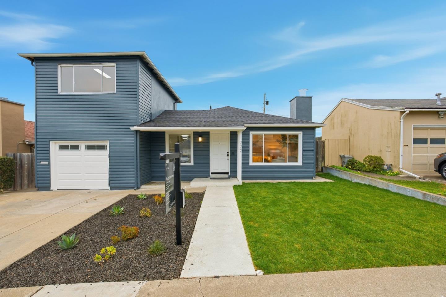 Blue two-story house with an attached garage, front lawn, and the number 227 beside the entrance.