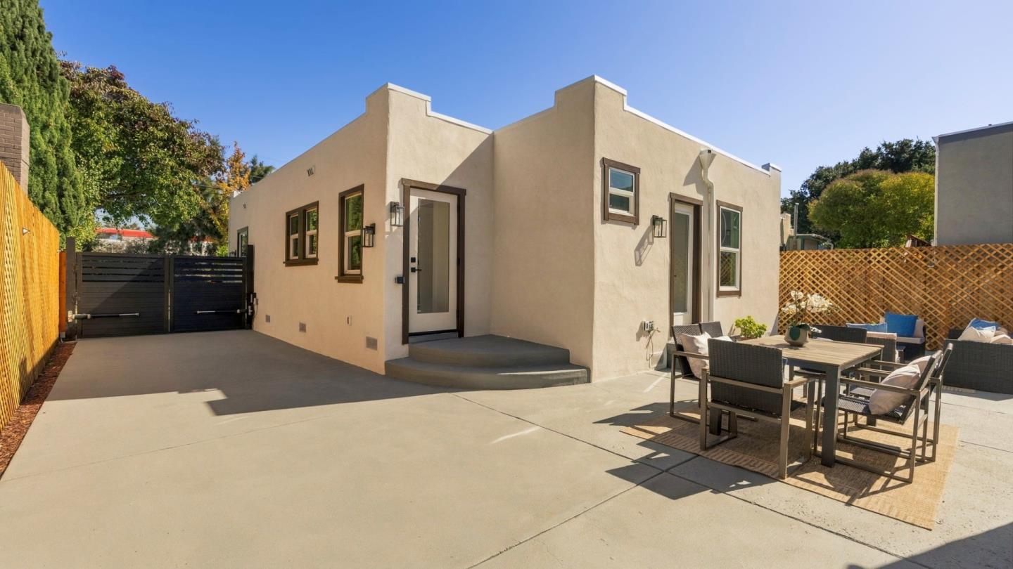 Stucco home with a concrete courtyard, outdoor dining set, and gated driveway.
