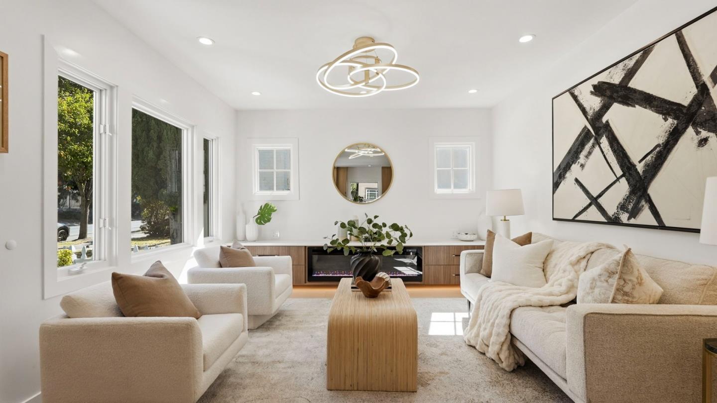 Staged living room with cream sofas, large windows, and a linear fireplace.
