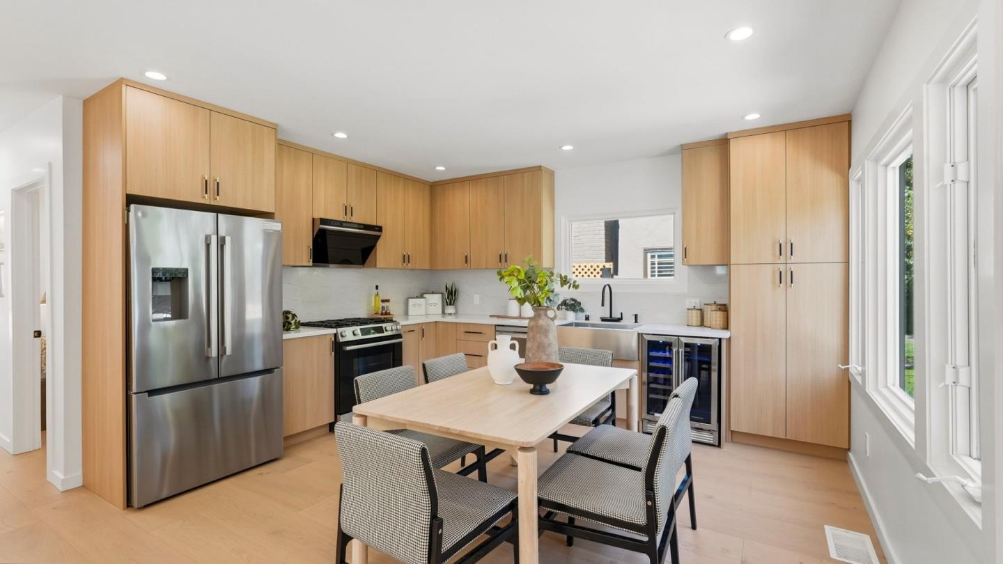 Kitchen with light wood cabinets, stainless steel appliances, and a dining table with four chairs.