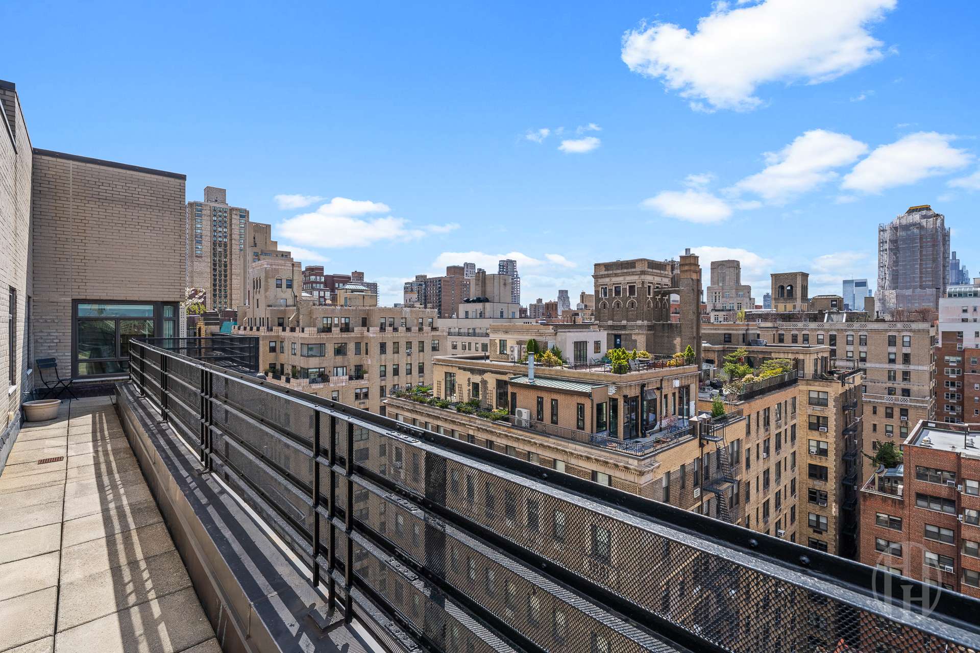 Rooftop terrace overlooking New York City buildings, with a tiled floor and black metal railing.