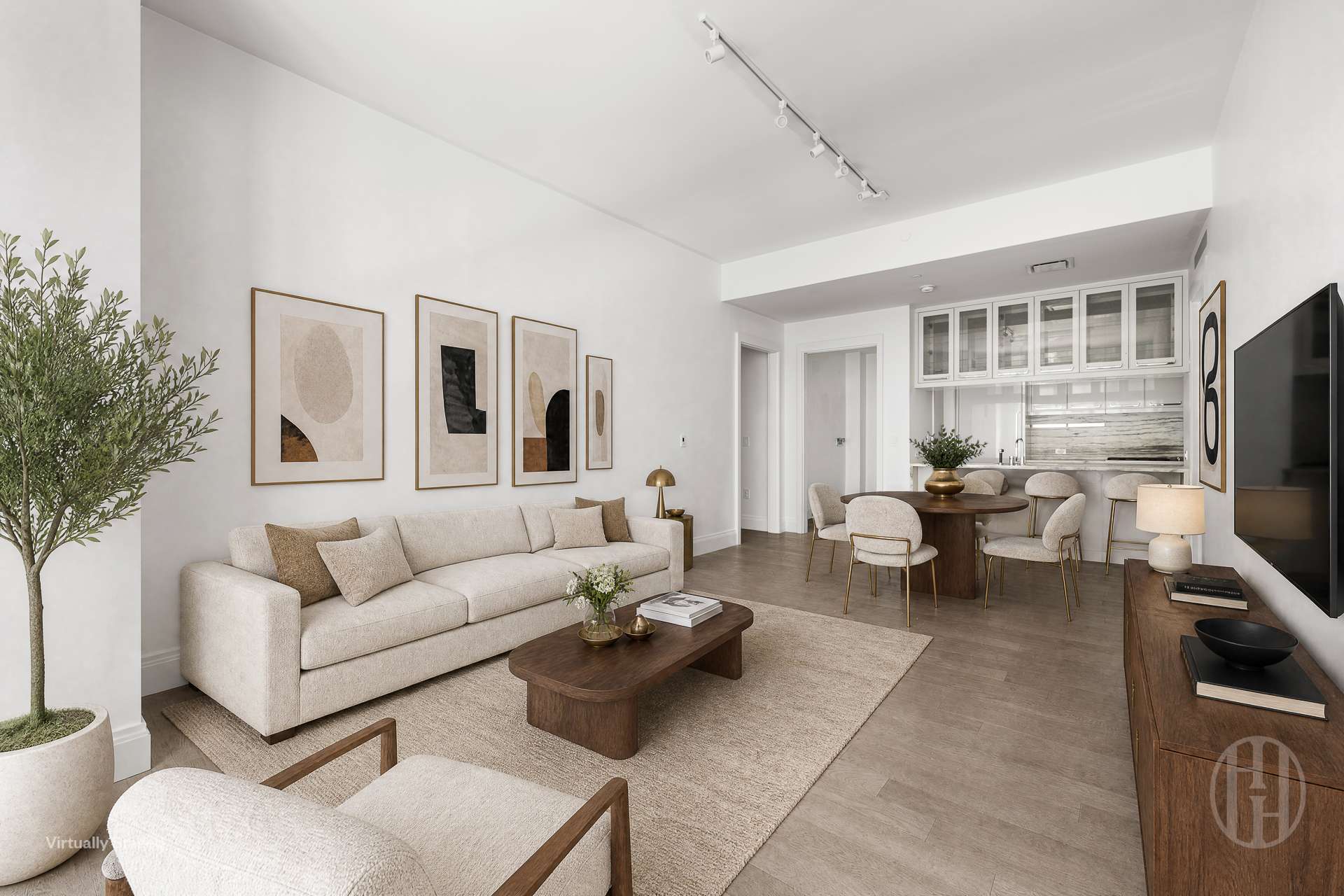 Open-plan living and dining room with a cream sofa, abstract art, round dining table, and glass-front kitchen cabinets.